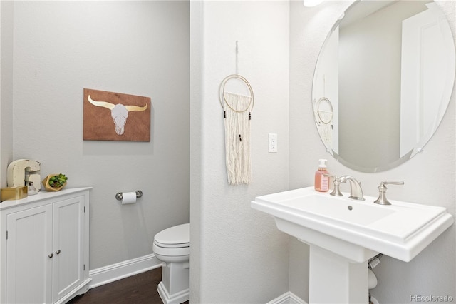 bathroom with wood finished floors, toilet, baseboards, and a sink