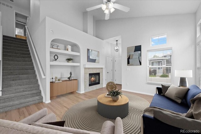 10685 Cherrybrook Cir, Highlands Ranch, CO 80126 - living room with high vaulted ceiling, stairs, built in shelves, ceiling fan, and light wood-style flooring