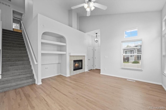 10685 Cherrybrook Cir, Highlands Ranch, CO 80126 - unfurnished living room with a towering ceiling, built in features, stairway, ceiling fan, and light wood finished floors