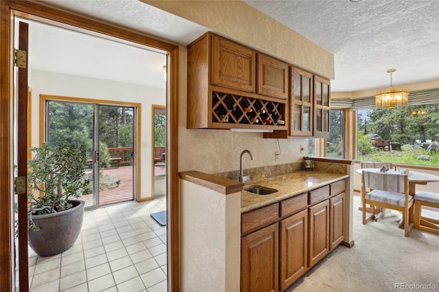 4992 White House Trl, Evergreen, CO 80439 - kitchen featuring a sink, a textured ceiling, brown cabinets, glass insert cabinets, and hanging light fixtures