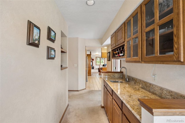 4992 White House Trl, Evergreen, CO 80439 - kitchen with a sink, brown cabinets, light carpet, glass insert cabinets, and light stone countertops