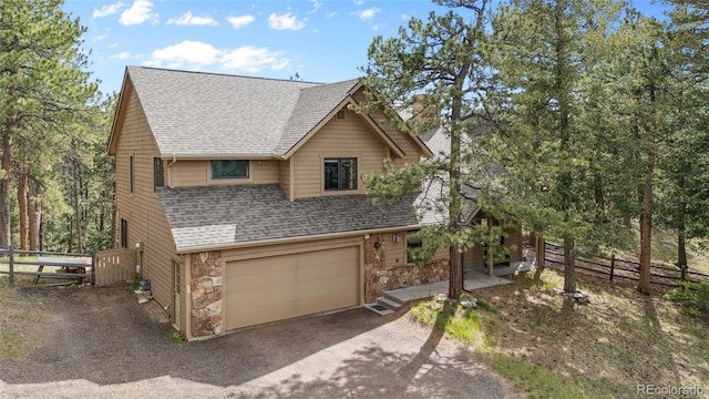 4992 White House Trl, Evergreen, CO 80439 - view of front facade featuring roof with shingles, stone siding, an attached garage, and driveway