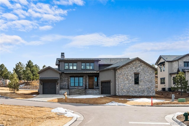 view of front of property featuring a garage, stone siding, a chimney, a standing seam roof, and stucco siding