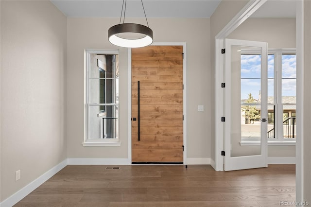 doorway to outside with wood finished floors, visible vents, and baseboards