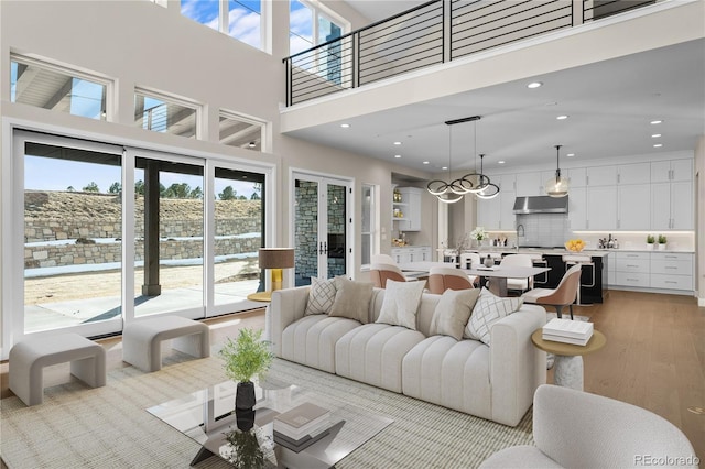 living area featuring a high ceiling, light wood-type flooring, a wealth of natural light, and recessed lighting