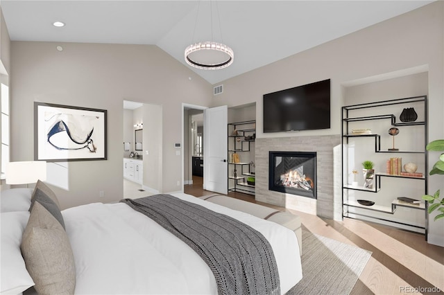 bedroom featuring lofted ceiling, a fireplace, wood finished floors, and visible vents