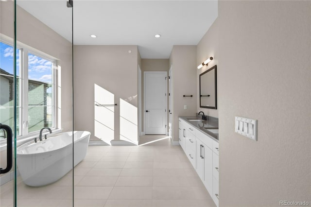 full bathroom with double vanity, recessed lighting, a sink, a freestanding tub, and tile patterned floors