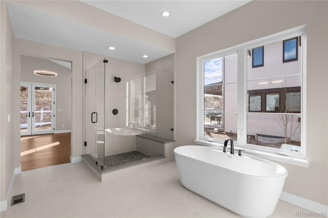 bathroom with visible vents, a freestanding bath, a shower stall, and a wealth of natural light