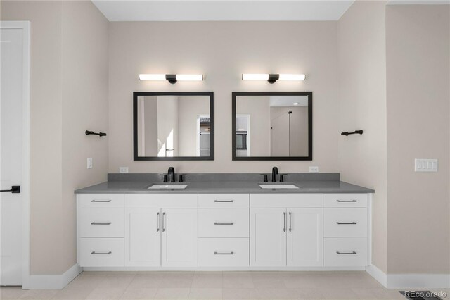 full bathroom featuring a sink, baseboards, and double vanity