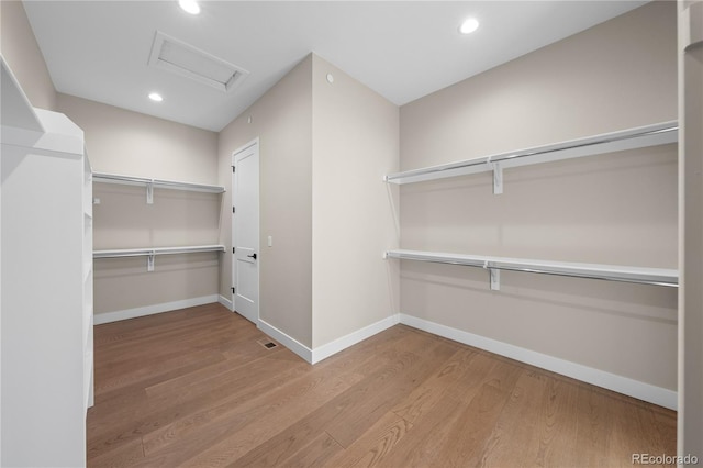 spacious closet with attic access, visible vents, and wood finished floors