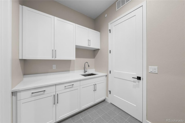 laundry area featuring light tile patterned floors, a sink, and visible vents