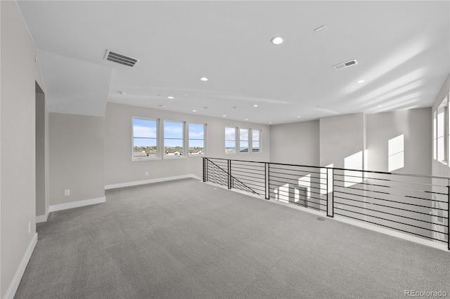 empty room with carpet, visible vents, baseboards, and recessed lighting