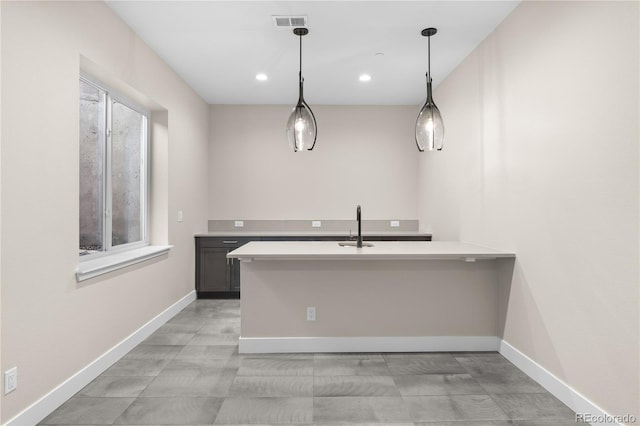 kitchen with decorative light fixtures, light countertops, visible vents, a peninsula, and baseboards