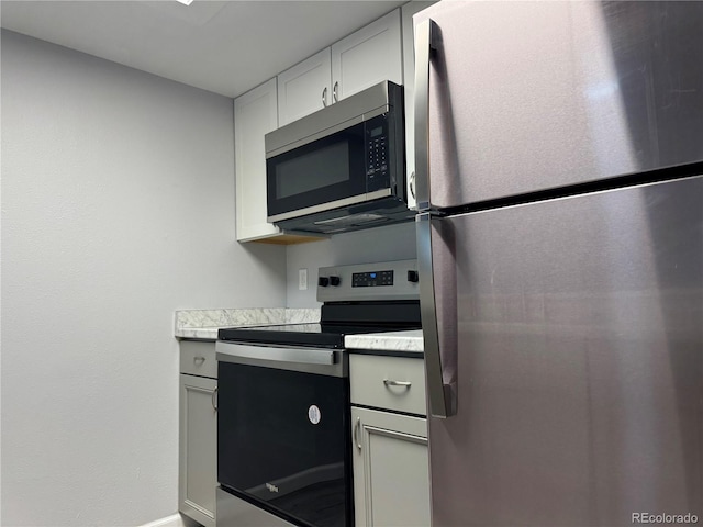 kitchen featuring stainless steel appliances, light countertops, and white cabinets