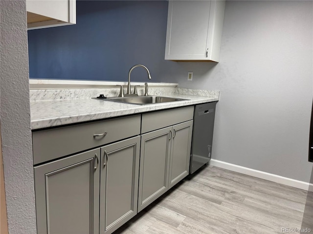 kitchen with a sink, gray cabinets, light countertops, and dishwasher