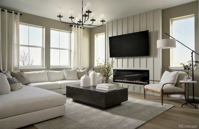 living room with a large fireplace, light wood finished floors, and an inviting chandelier