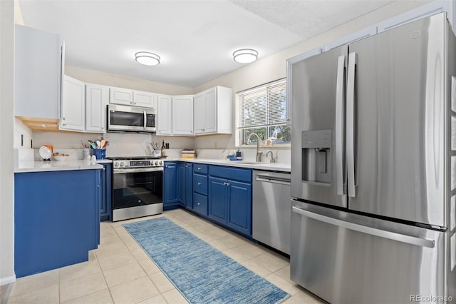 1204 Catalpa Cir, Broomfield, CO 80020 - kitchen featuring appliances with stainless steel finishes, blue cabinets, light countertops, and light tile patterned floors
