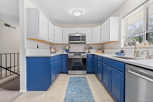 1204 Catalpa Cir, Broomfield, CO 80020 - kitchen featuring appliances with stainless steel finishes, blue cabinets, light countertops, white cabinets, and light tile patterned floors