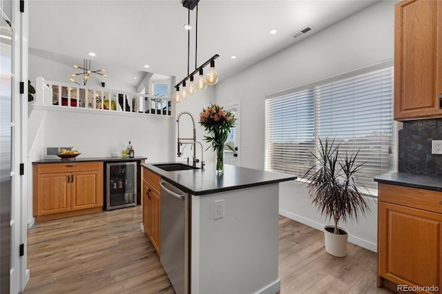 kitchen featuring beverage cooler, light wood finished floors, a sink, stainless steel dishwasher, and dark countertops