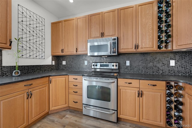 kitchen featuring decorative backsplash, appliances with stainless steel finishes, and light wood-style floors