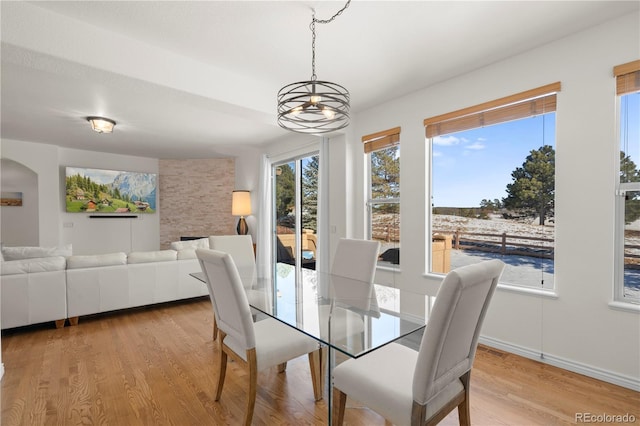 dining area featuring light hardwood / wood-style flooring, a notable chandelier, and a stone fireplace