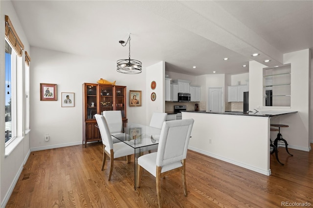 dining area with light wood-type flooring, an inviting chandelier, and plenty of natural light