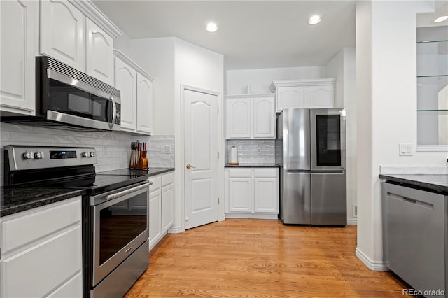 kitchen featuring white cabinets, light wood-type flooring, stainless steel appliances, and backsplash