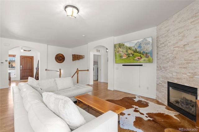 2663 Cinnabar Rd, Colorado Springs, CO 80921 - living area featuring washer / clothes dryer, a stone fireplace, visible vents, arched walkways, and light wood finished floors