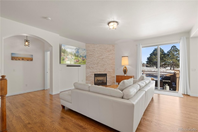 2663 Cinnabar Rd, Colorado Springs, CO 80921 - living area featuring arched walkways, baseboards, a fireplace, and light wood-type flooring