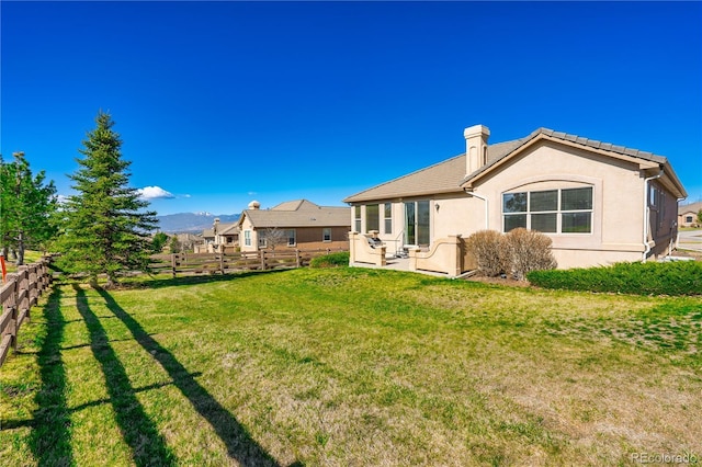 2663 Cinnabar Rd, Colorado Springs, CO 80921 - rear view of house featuring stucco siding, a lawn, fence, and a chimney
