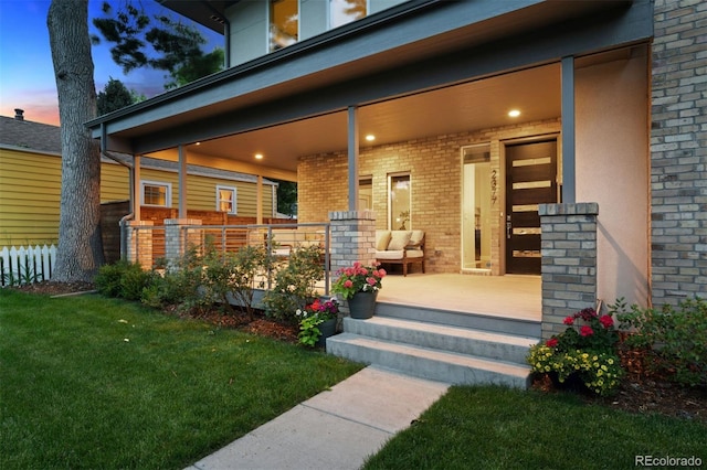 2377 S Humboldt St, Denver, CO 80210 - exterior entry at dusk with covered porch, brick siding, and a yard