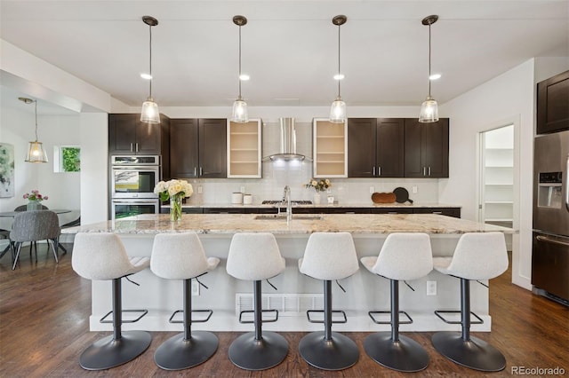 2377 S Humboldt St, Denver, CO 80210 - kitchen with stainless steel appliances, wall chimney range hood, dark brown cabinetry, and dark wood finished floors