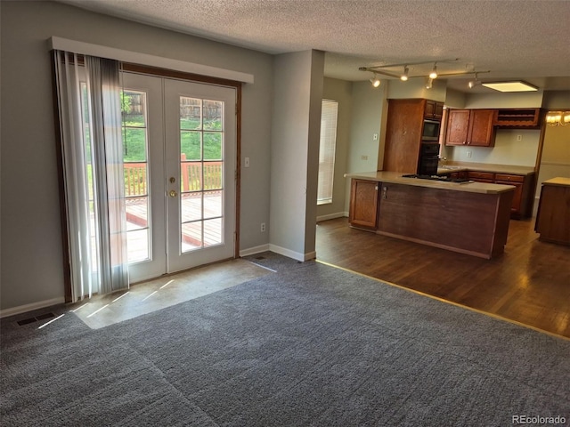 16835 E Harvard Pl, Aurora, CO 80013 - kitchen with dark colored carpet, brown cabinetry, a peninsula, french doors, and a textured ceiling