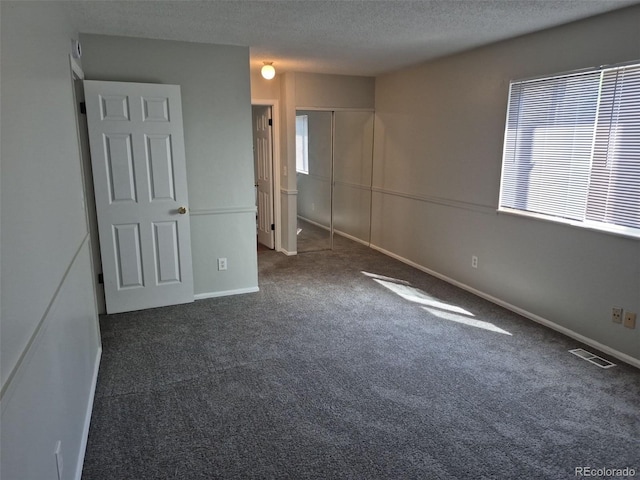 16835 E Harvard Pl, Aurora, CO 80013 - unfurnished bedroom with carpet floors, multiple windows, a textured ceiling, a closet, and baseboards