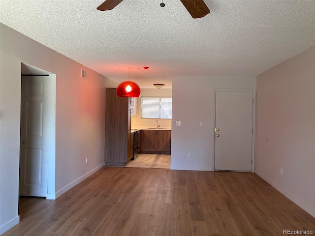 spare room featuring ceiling fan, sink, wood-type flooring, and a textured ceiling