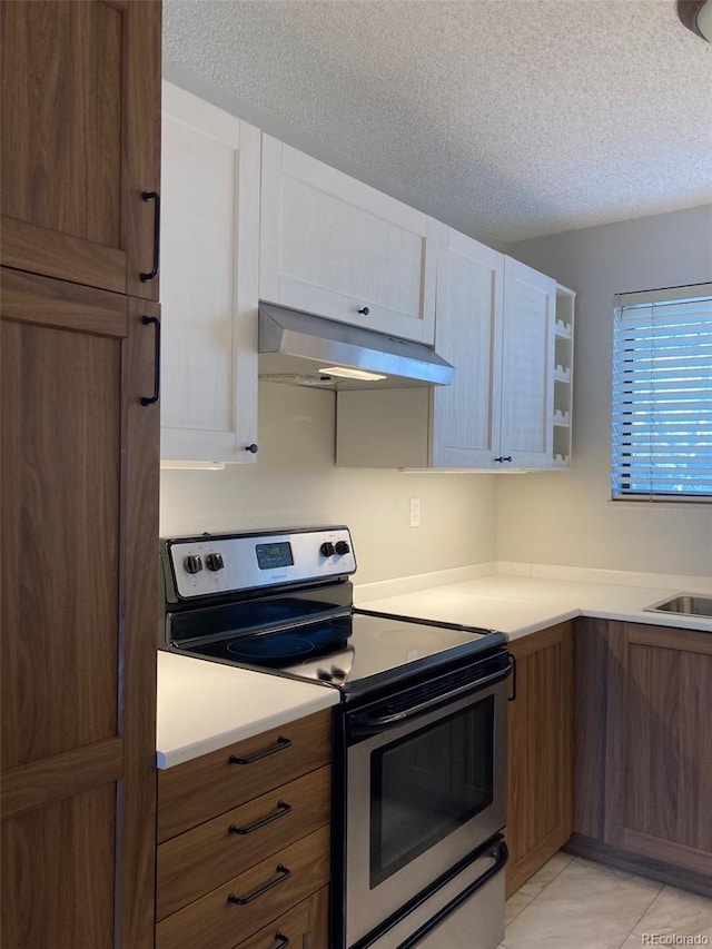 kitchen featuring stainless steel electric range oven, light tile patterned floors, white cabinets, and a textured ceiling