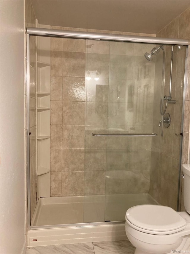 bathroom with a shower with shower door and toilet