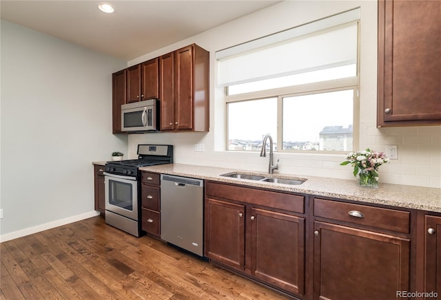 10154 Belvedere Loop, Lone Tree, CO 80124 - kitchen with appliances with stainless steel finishes, a sink, dark wood-style floors, baseboards, and light stone countertops