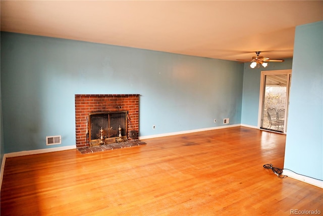 unfurnished living room featuring a brick fireplace, hardwood / wood-style floors, and ceiling fan