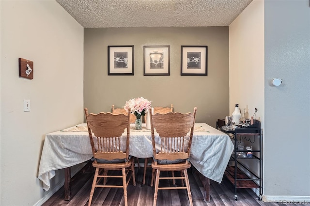 dining area with wood finished floors, a textured ceiling, and baseboards
