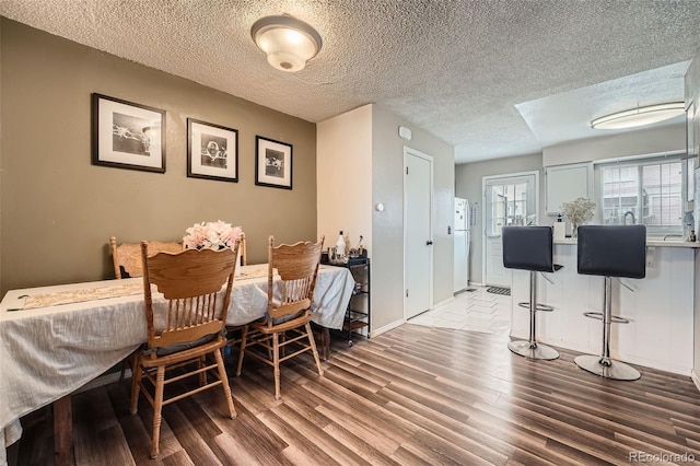 dining room featuring wood finished floors, a textured ceiling, and baseboards