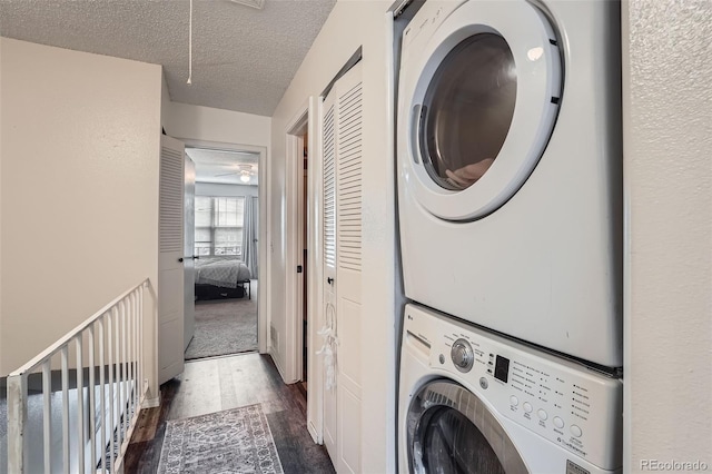 washroom with stacked washer / drying machine, dark wood-style floors, attic access, and a textured ceiling