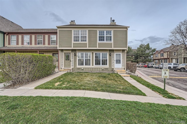 view of property with a front yard, a chimney, entry steps, and uncovered parking