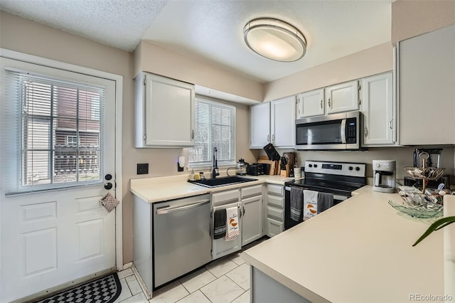 kitchen featuring stainless steel appliances, a sink, light countertops, and a textured ceiling