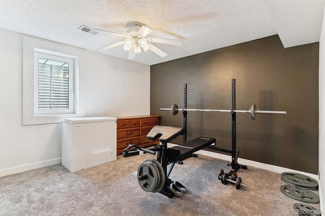 exercise room with carpet, baseboards, visible vents, ceiling fan, and a textured ceiling