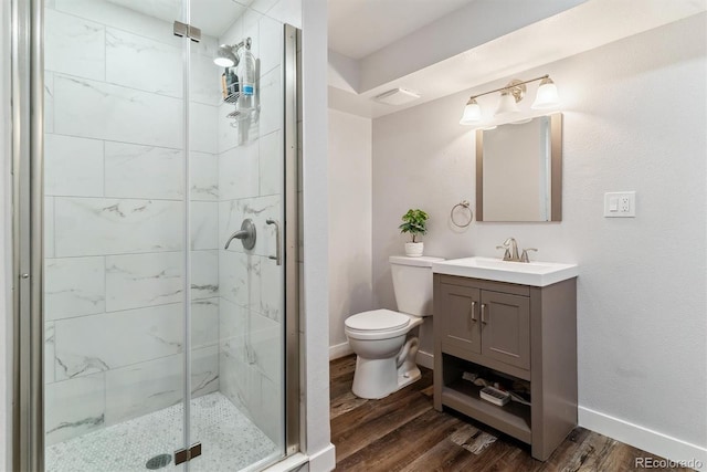 bathroom featuring toilet, a stall shower, wood finished floors, baseboards, and vanity