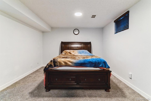 bedroom with visible vents, a textured ceiling, baseboards, and carpet