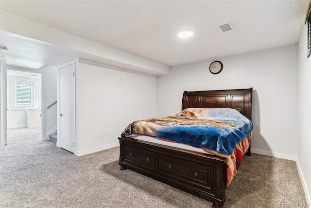 bedroom featuring visible vents, baseboards, light colored carpet, and a textured ceiling