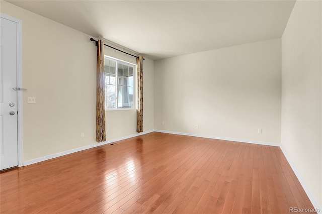 spare room with baseboards, visible vents, and light wood-style floors