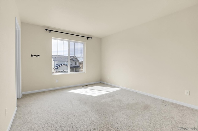 spare room featuring carpet floors, baseboards, and visible vents